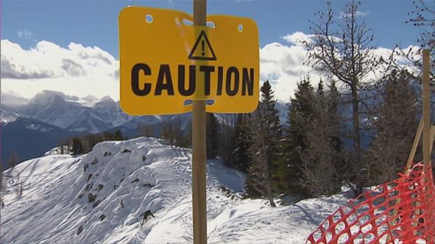 A yellow caution sign on a snowy mountain.