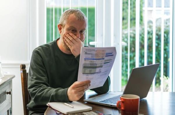 Worried man checking bills at home