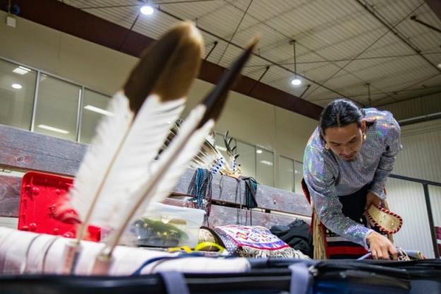 A man dresses in powwow regalia.