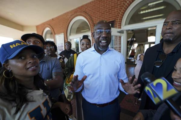 Democratic nominee for U.S Senate Sen. Raphael Warnock speaks to a reporter during a campaign stop on the campus of Morehouse College Tuesday, Nov. 8, 2022, in Atlanta. 