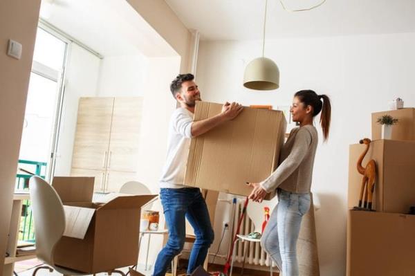 Young couple carrying big cardboard box at new home.Moving house.