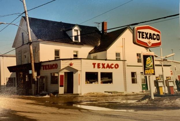 An old photo of a white building with a red sign reading 