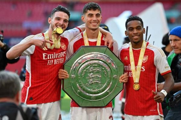 The new signings, Arsenal's English midfielder Declan Rice (L), Arsenal's German midfielder Kai Havertz (C) and Arsenal's Dutch defender Jurrien Timber (R) pose with the trophy as Arsenal players celebrate winning the English FA Community Shield football match between Arsenal and Manchester City at Wembley Stadium, in London, August 6, 2023. (Photo by JUSTIN TALLIS / AFP) 