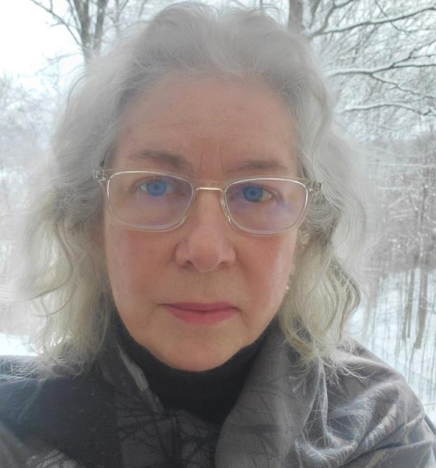 A woman wearing glasses stands outside during winter.