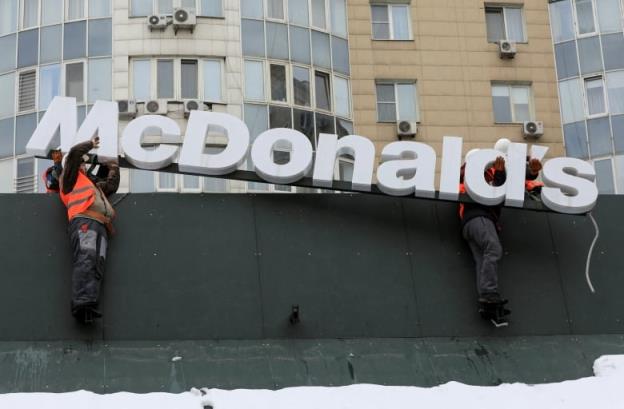 Workers remove the lettering spelling the word 