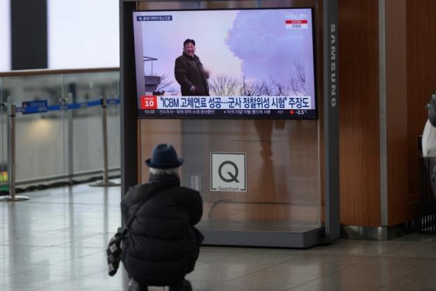 A person sits while watching a TV showing an image of North Korean leader Kim Jong-un.