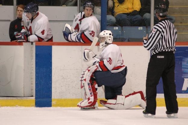 A goalie is shown kneeling on the ice. 