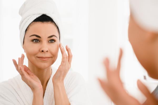 Woman putting makeup on using the bathroom mirror.