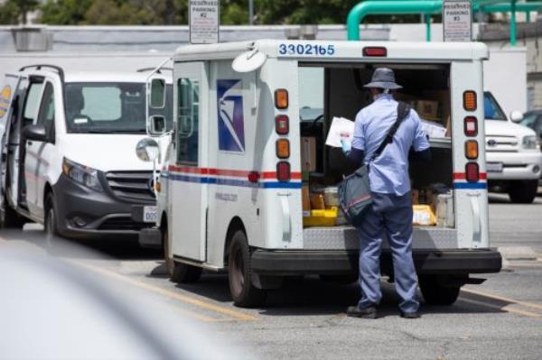 A USPS (United States Parcel Service) mail truck and postal carrier make a delivery.