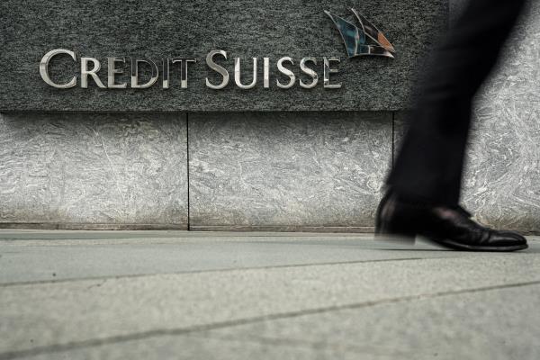 Pedestrian walks past a logo of Credit Suisse outside its office building in Hong Kong