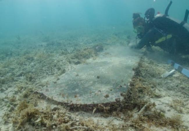 diver underwater looking at a gravestone