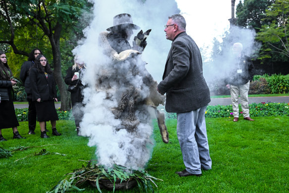 First Peoples Assembly of Victoria members pass through smoke next to the Sir Doug and Lady Gladys Nicholls statue.