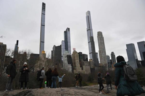 People pose in front of high rise buildings at Central Park in New York City on Friday, Jan. 13, 2023. 