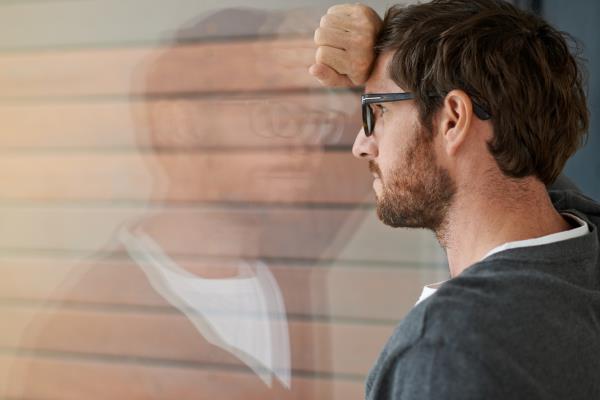 Man leaning his head against a window.