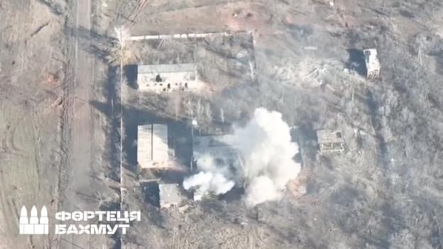 An aerial view of a smoking rural building.