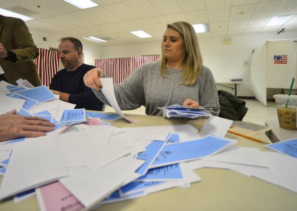 Megan Kondrat, of Hinsdale, N.H., puts the primary ballots into piles before they start to count the votes at the Millstream Community Center, in Hinsdale, N.H.,after the closing of the polls during the New Hampshire presidential primary elections on Tuesday, Feb. 11, 2020. 