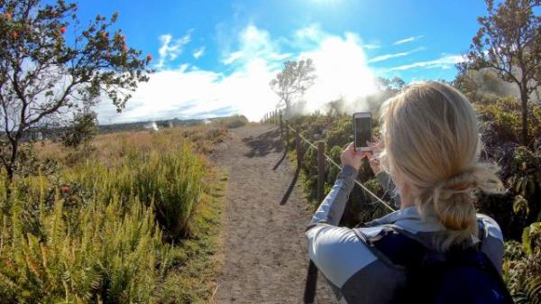 A woman taking a photo of the crater rim of a volcano