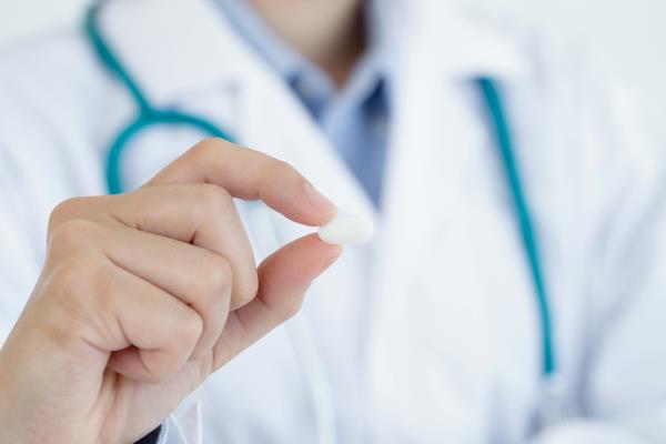 Doctor holding a capsule between her fingers. 