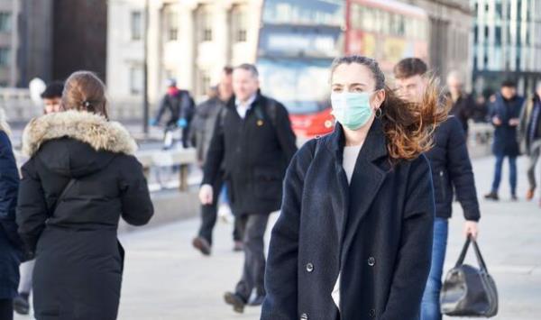 A woman walking a Lo<em></em>ndon street in a face mask