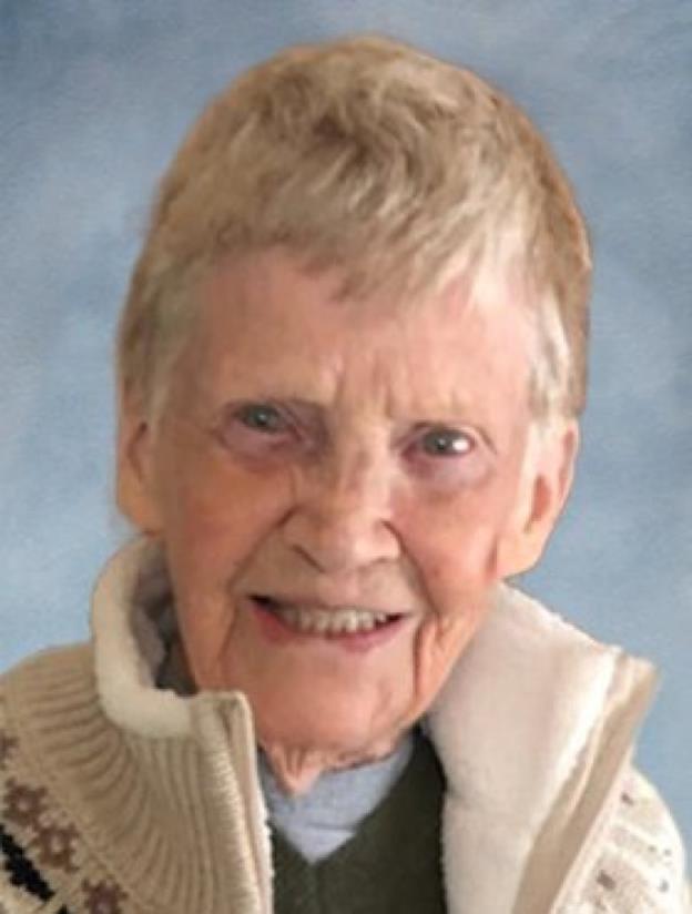 A older woman with short hair smiles. She is wearing a white fleece sweater with a long collar. 