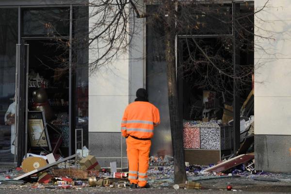 A public worker stands in debris in front of a chocolate store in Berlin, Germany, Friday, Dec. 16, 2022. 